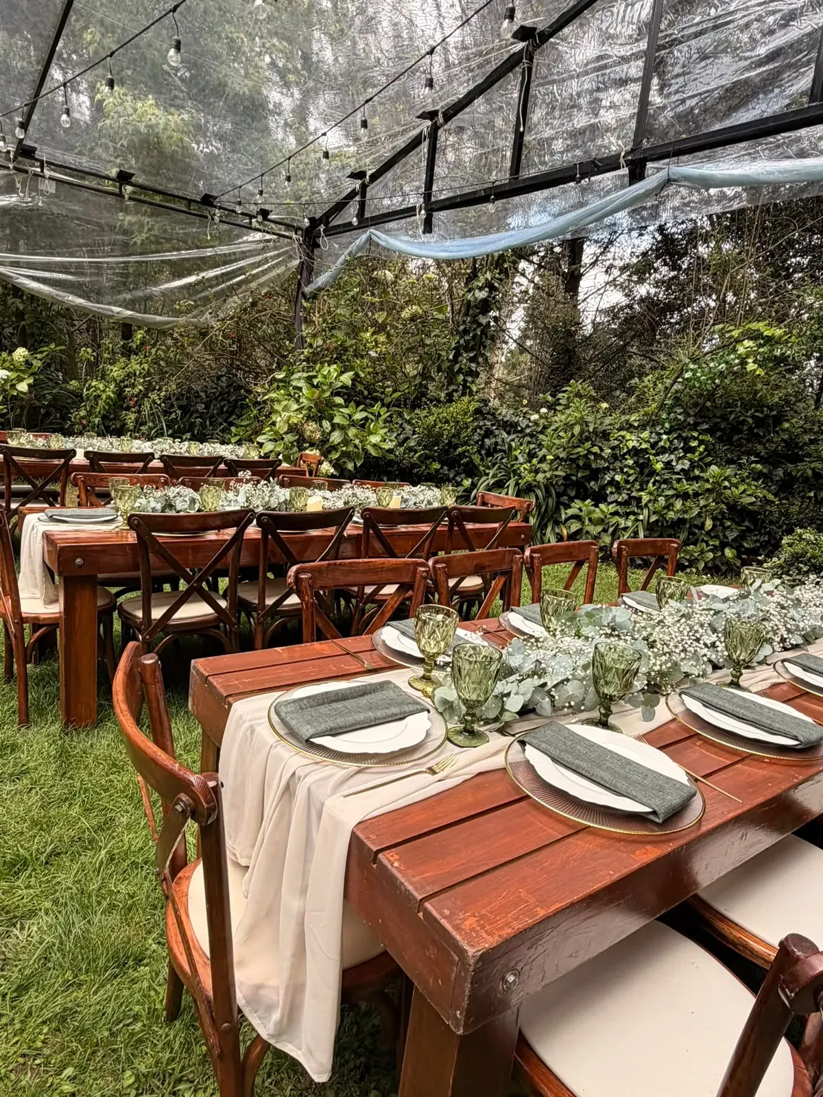 Mesas largas de madera para boda en jardín con copas verdes